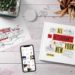 Wooden desktop with a plant, an art print, an iphone, a book, and a cup of pencils